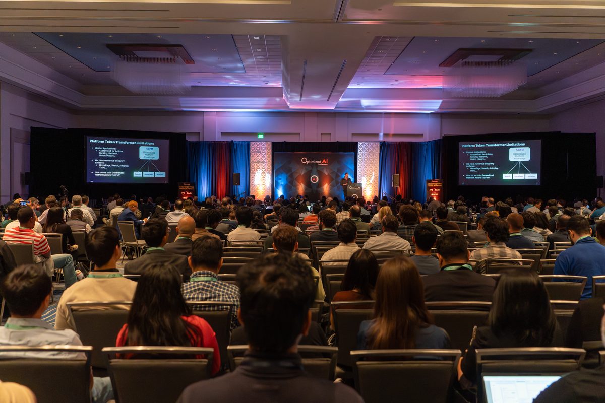 Attendees seated for a general session talk with slides on both screens