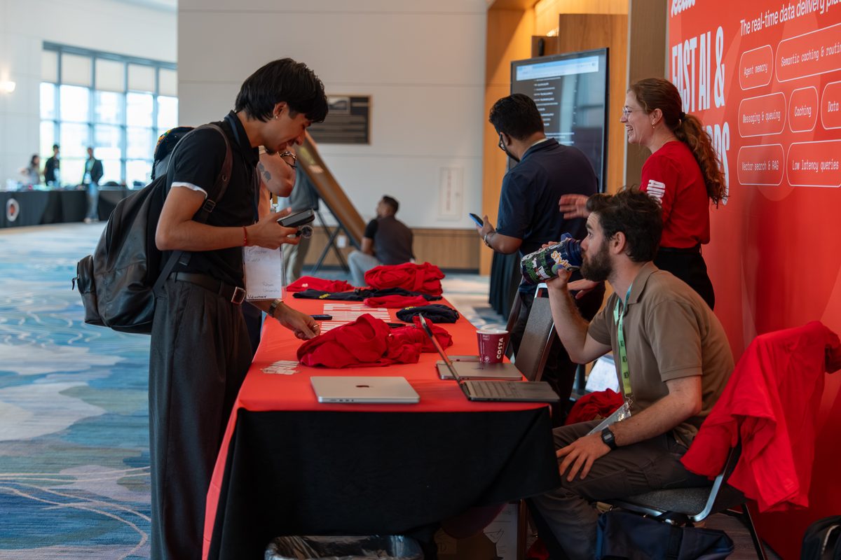Attendees picking up swag at the Redis booth